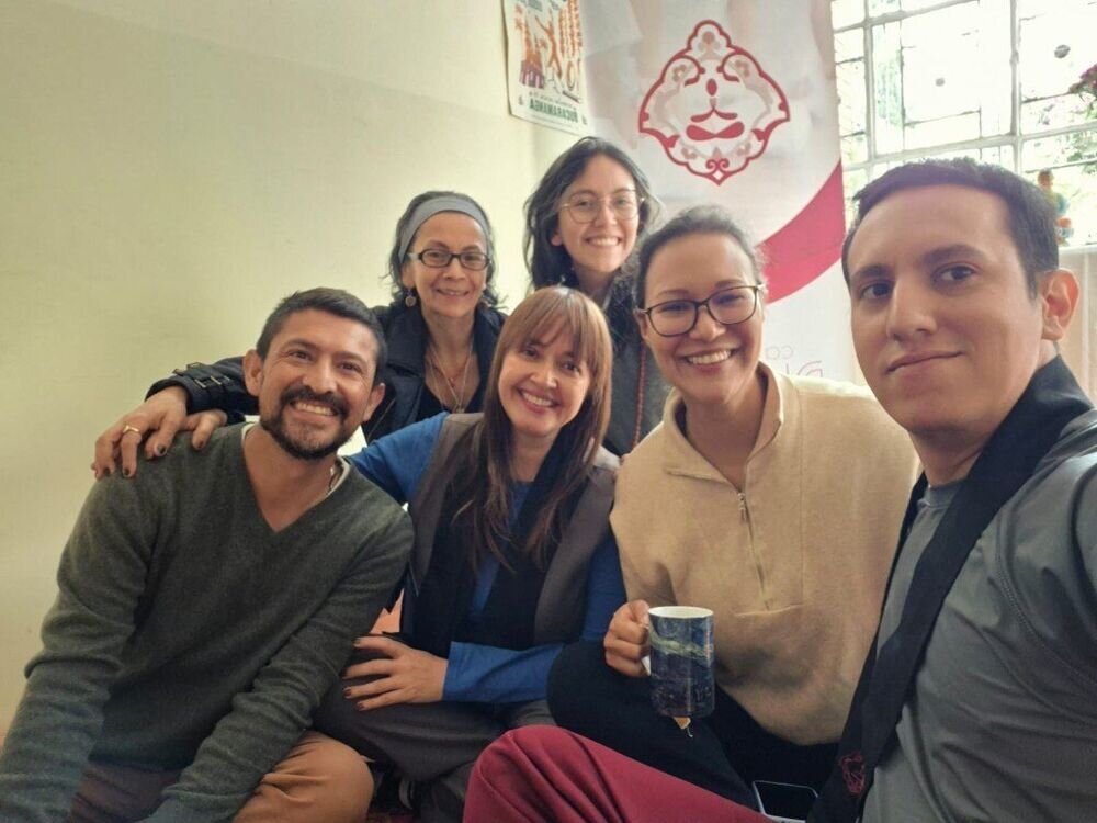 Selfie grupal de seis personas sentadas en un salón, sonriendo junto a un pendón de Camino del Dharma.