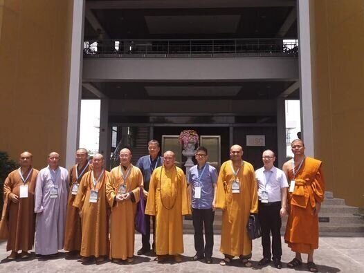 Diez monjes budistas de pie frente a un edificio moderno.